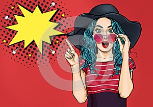 Pop Art Woman surprised in hat and glasses showing product .Beautiful girl with curly hair pointing to on bubble .