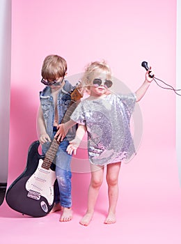 Pop Culture: Children a boy with a guitar and a girl with a microphone pretend to be popular musicians and perform a