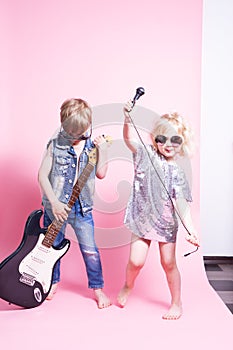 Pop Culture: Children a boy with a guitar and a girl with a microphone pretend to be popular musicians and perform a home concert