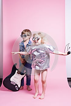 Pop Culture: Children a boy with a guitar and a girl with a microphone pretend to be popular musicians and perform a home concert