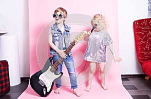 Pop Culture: Children a boy with a guitar and a girl with a microphone pretend to be popular musicians and perform a home concert