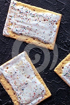 Pop tarts on black. Poptart toaster pastry with icing, shot from above