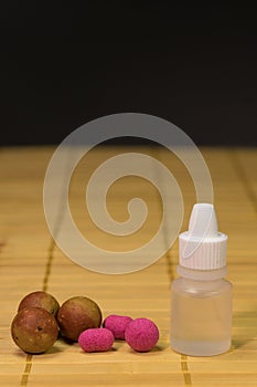 Pop up boilies. Close up view of crimson boilies, flavor bottle, fishing baits for carp on rwooden background