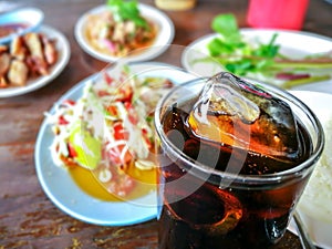 Pop water or cola in glass with ice cubes.