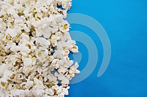 Popcorn on a blue background divides the picture into two parts. View from above. Copy space.