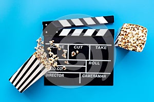 Popcorn with clapperboard and movie film reel. Cinema background