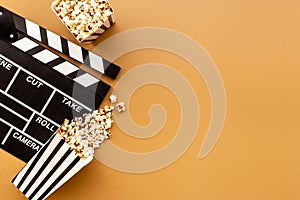 Popcorn with clapperboard and movie film reel. Cinema background