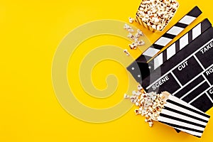 Popcorn with clapperboard and movie film reel. Cinema background