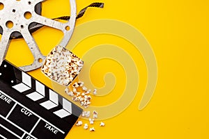 Popcorn with clapperboard and movie film reel. Cinema background