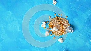 Popcorn falling on a light bulb shape on blue