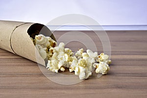 Popcorn falling from paper packaging with wood background