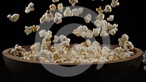 Popcorn falls into a wooden bowl
