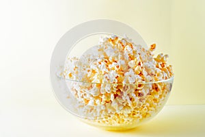 Popcorn in a glass bowl on a bright yellow background