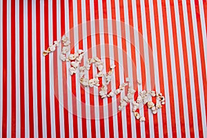 Popcorn grains arranged in movie word on red white striped background.