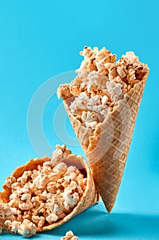 Popcorn in ice cream cones on blue background.