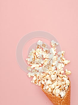 Popcorn in ice cream cones on pink background. Top view