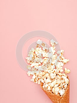 Popcorn in ice cream cones on pink background. Top view