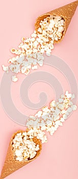 Popcorn in ice cream cones on pink background. Top view