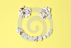 Popcorn laid out in the form of happy smilies on a yellow background close-up