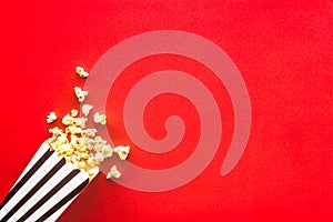 Popcorn in paper bag scattered on red background top view copy space