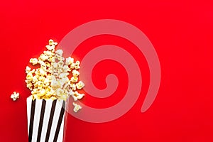 Popcorn in paper bag scattered on red background top view copy space