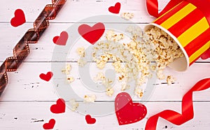 Popcorn, red hearts and ribbon on a white wooden background. valentine`s day, movie theater