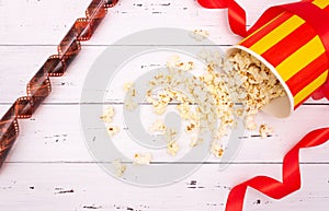 Popcorn, red ribbon on white wooden background. Valentine`s day, movie theater
