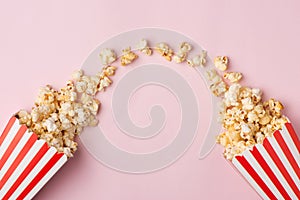 Popcorn in red and white cardboard box on the pink background.