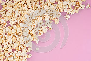 Popcorn scattered at half the pastel pink background and a space for copyspace. Popcorn on a red background