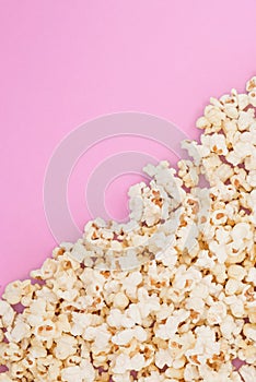 Popcorn scattered at half the pastel pink background and a space for copyspace. Popcorn on a red background. Flat lay