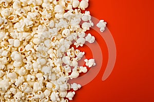 Popcorn scattered on a red background. A classic movie theater snack. View from above