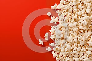 Popcorn scattered on a red background. A classic movie theater snack. View from above