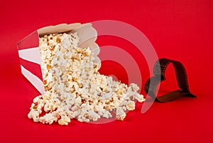 Popcorn spilled on blue background and film in heart form