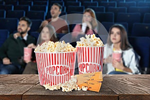 Popcorn, tickets on table and people in cinema hall