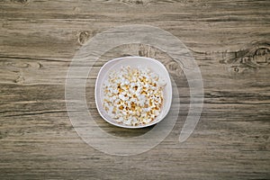 Popcorn in a white bowl top view. Fresh pop corn in white blow on wood table background. White Salty popcorn a full bowl.