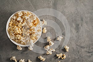 Popcorn in a white plate on a concrete background
