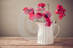 Poppy flower bouquet in white jug on wooden table