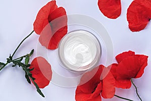 Poppy flowers and white cosmetic cream jar. Natural organic handmade cosmetics concept. Top view