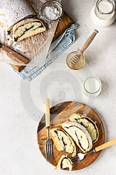 Poppy seed roll or strudel on wooden board sprinkled with powdered sugar.