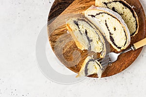 Poppy seed roll or strudel on wooden board sprinkled with powdered sugar.