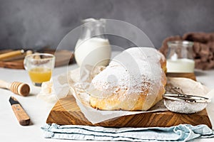 Poppy seed roll or strudel on wooden board sprinkled with powdered sugar.