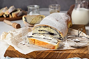 Poppy seed roll or strudel on wooden board sprinkled with powdered sugar.