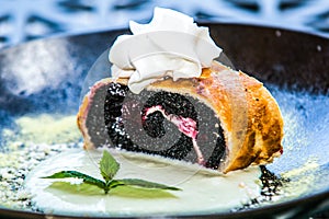 Poppy seed strudel sprinkled with powdered sugar and mint leaf