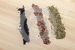 Poppy seeds, oregano and linseed on wood surface