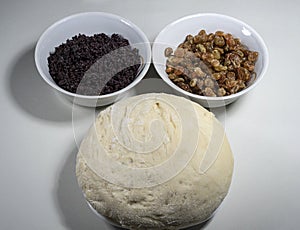 Poppy seeds, raisins and raw yeast dough in white plates.