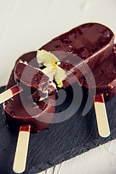 Popsicle with grated chocolate on a wooden background
