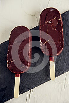 Popsicle with grated chocolate on a wooden background