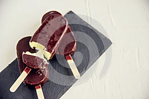 Popsicle with grated chocolate on a wooden background