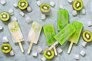 Popsicles kiwi lying on a gray background with ice cubes. The view from above, flat lay. The concept of summer. Summer dessert.