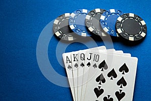 A popular and exciting poker game with a winning combination of royal flush. Playing cards and chips on a blue table in a poker